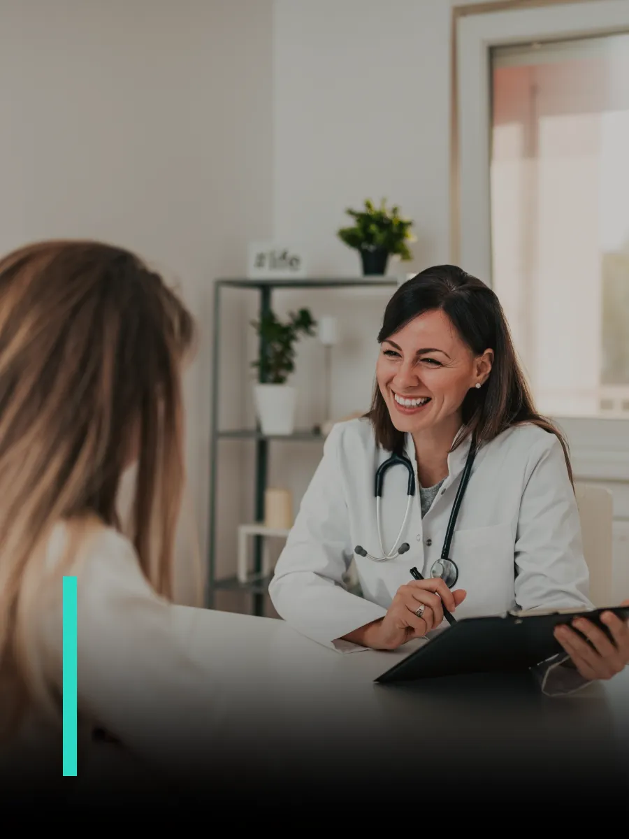 Una doctora sonríe mientras atiende a su paciente